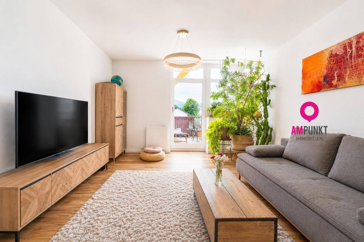 Helles Wohnzimmer mit Sofa, TV-Möbeln und Zugang zu einem sonnigen Balkon.