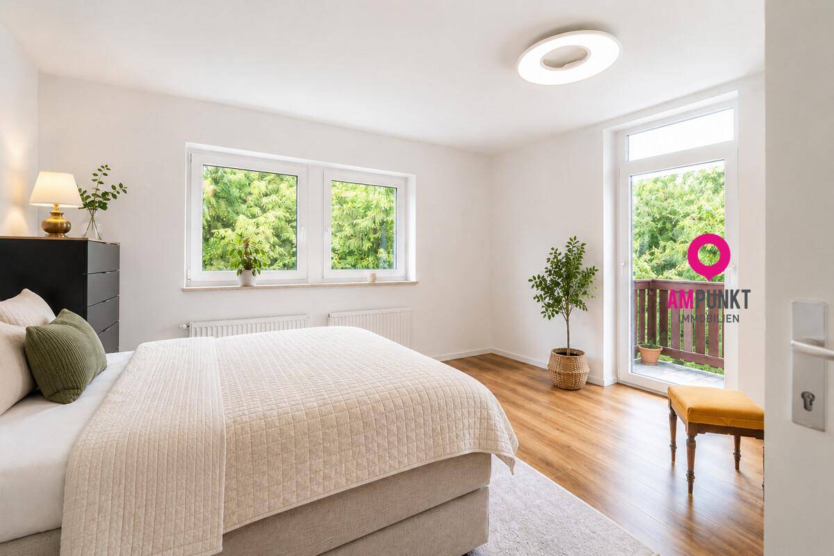 Geräumiges Schlafzimmer mit großem Bett, viel Tageslicht und Zugang zum Balkon.