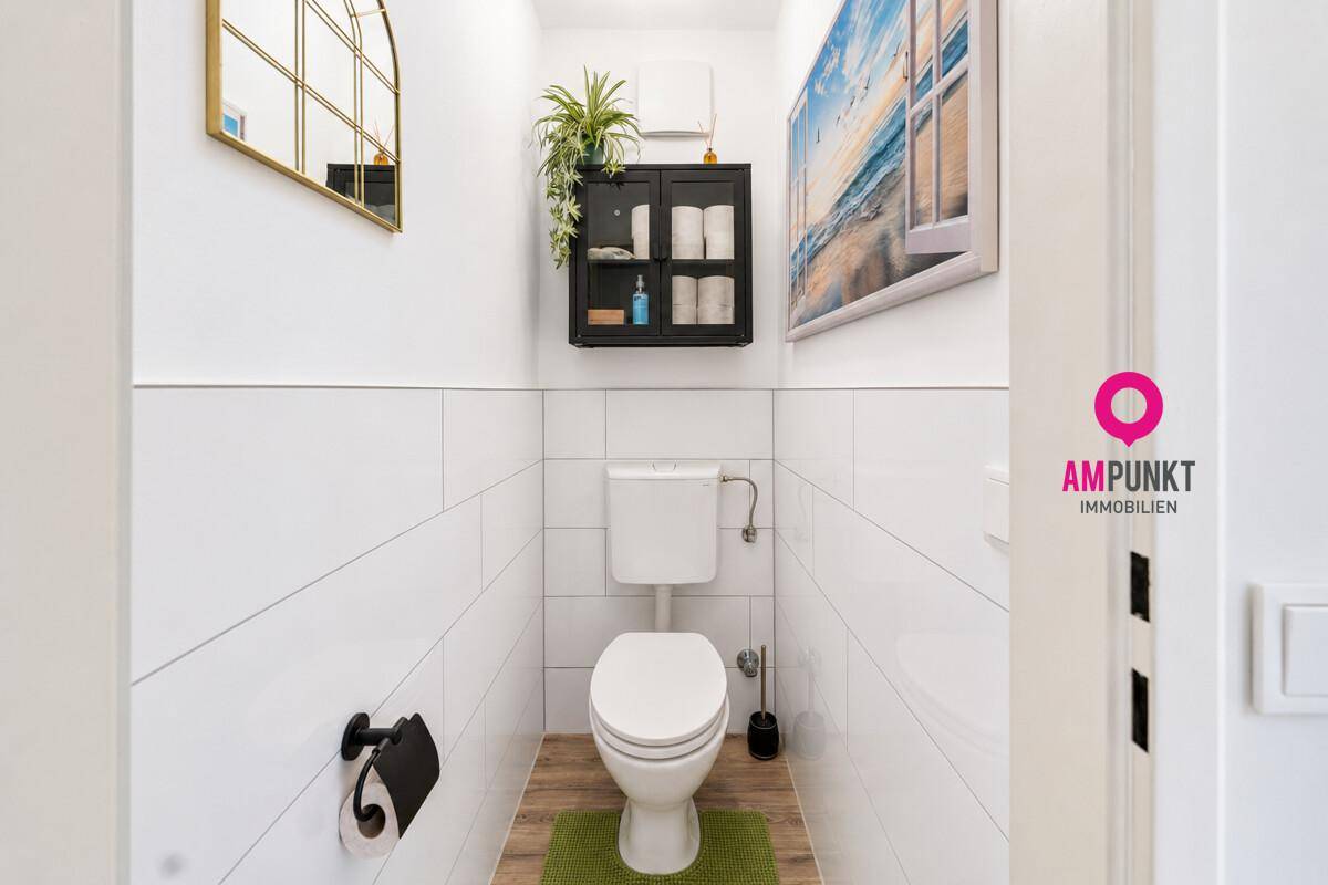 Kleines, helles Gäste-WC mit Wand-WC, Spiegel und modernen Fliesen.
