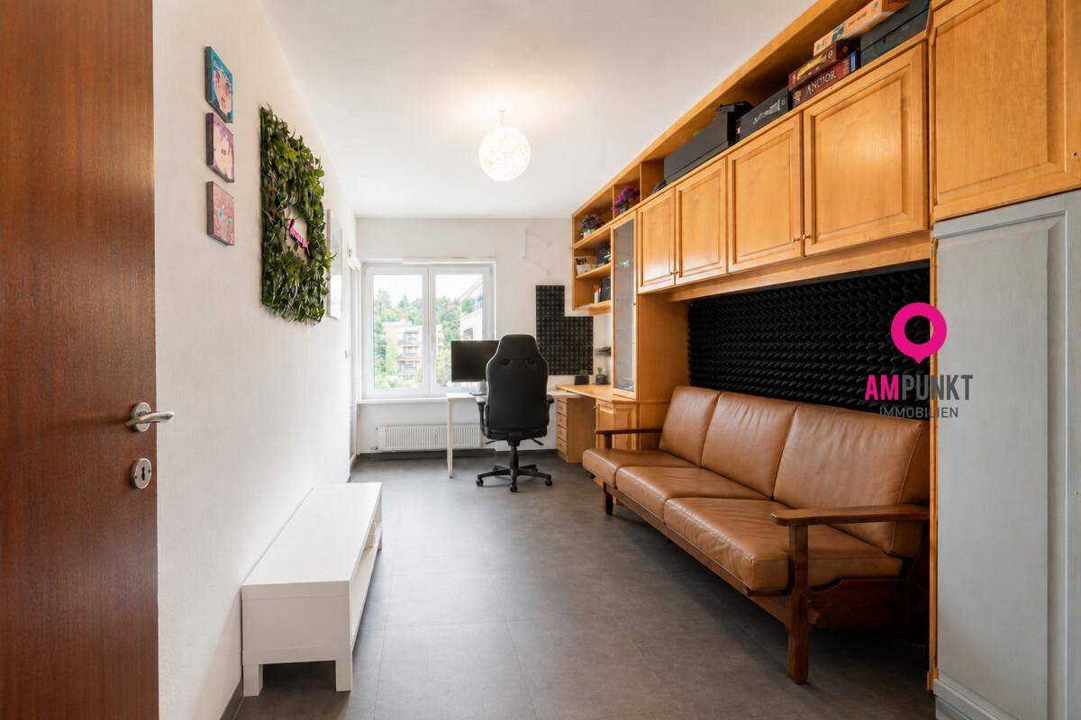 Arbeitszimmer mit braunem Ledersofa, Einbauschränken und schallgedämmter Wand.