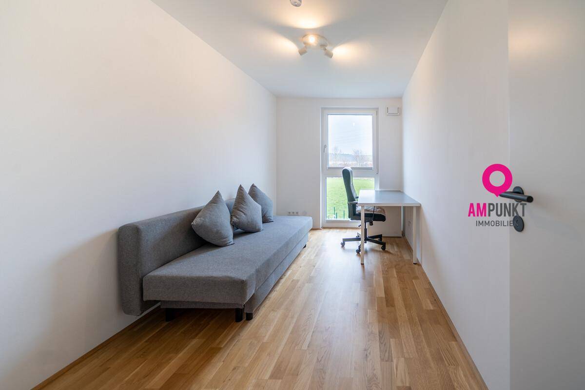Helles Arbeitszimmer mit Sofa, Schreibtisch und Blick ins Grüne.