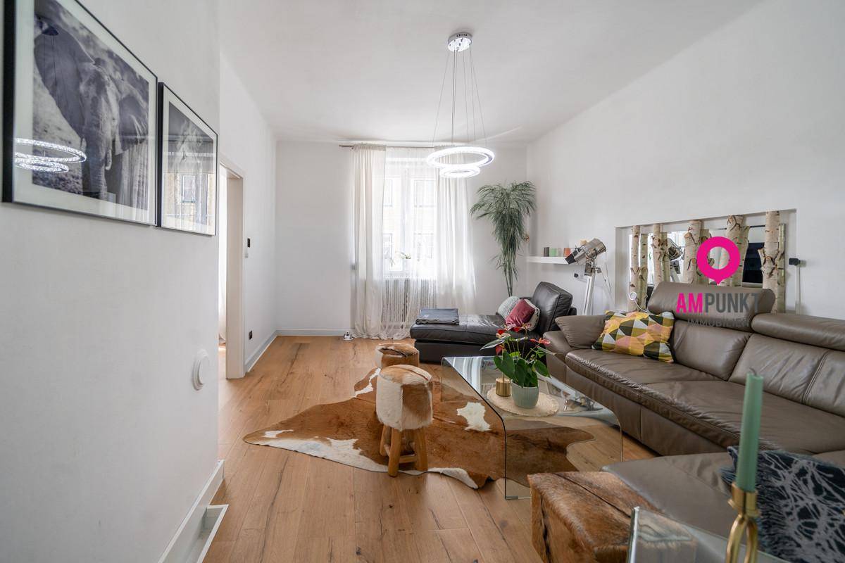 Gemütliches Wohnzimmer mit großem Ledersofa, Holzboden und dekorativem Kuhfellteppich.
