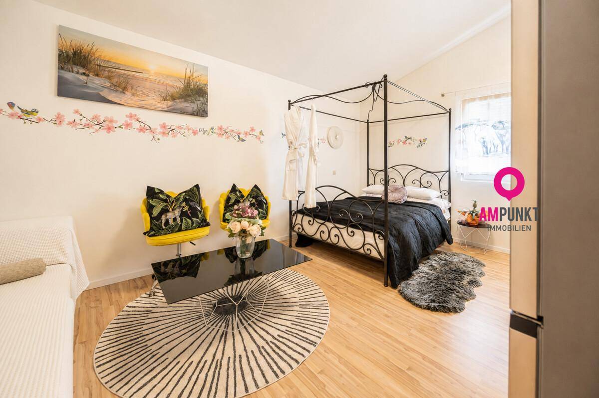 Schlafzimmer mit Himmelbett, Holzboden und farbenfroher Dekoration, einladend und hell.