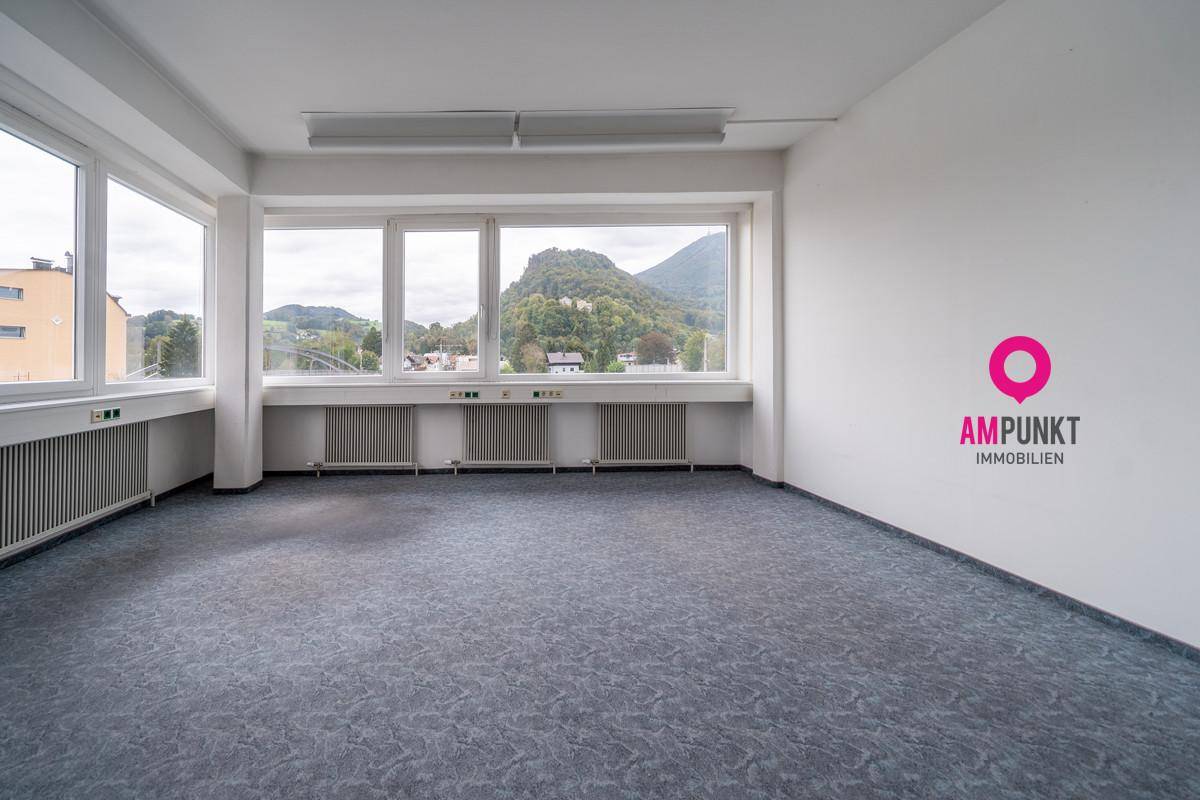 Heller Büroraum mit Teppichboden und großen Fenstern, die einen schönen Bergblick bieten.
