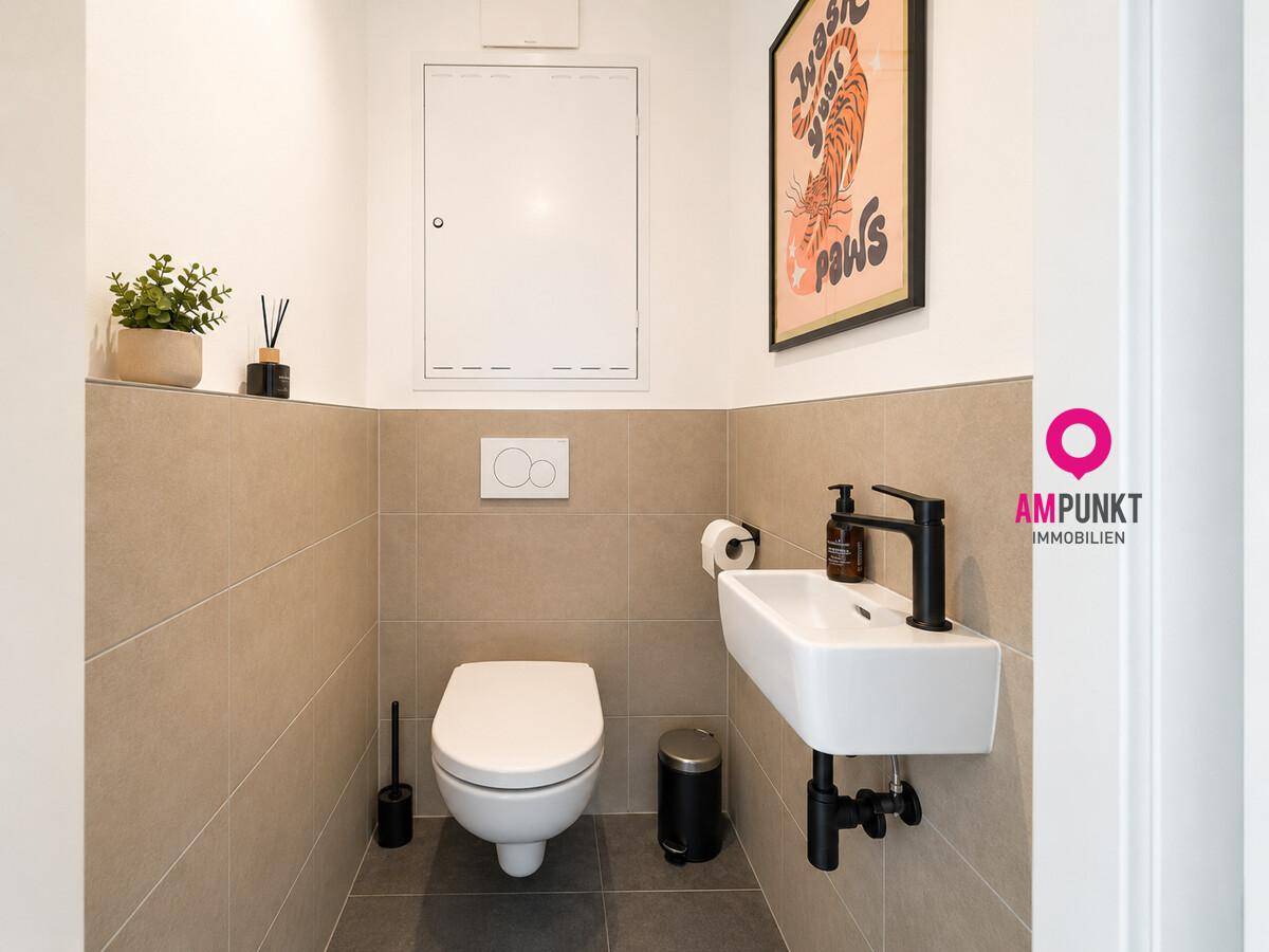 Kleines Gäste-WC mit beigefarbenen Fliesen, wandhängendem WC und modernem Waschbecken.