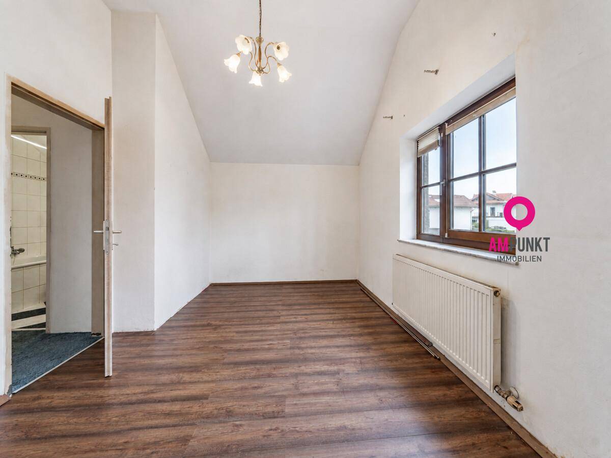 Schlafzimmer im Dachgeschoss mit Laminatboden, Dachschräge und großem Fenster.