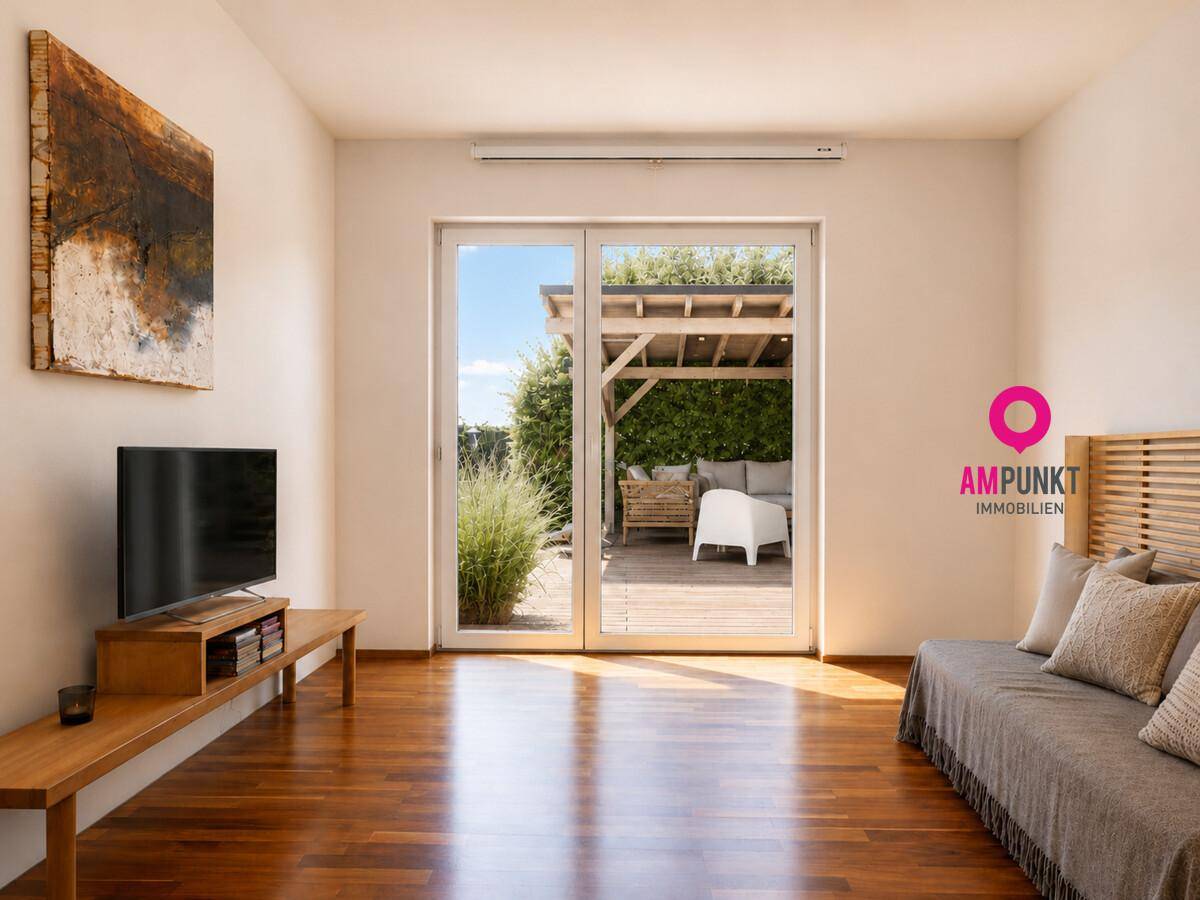 Gemütliches Wohnzimmer mit Holzboden, Sofa und Zugang zu einer Außenterrasse.