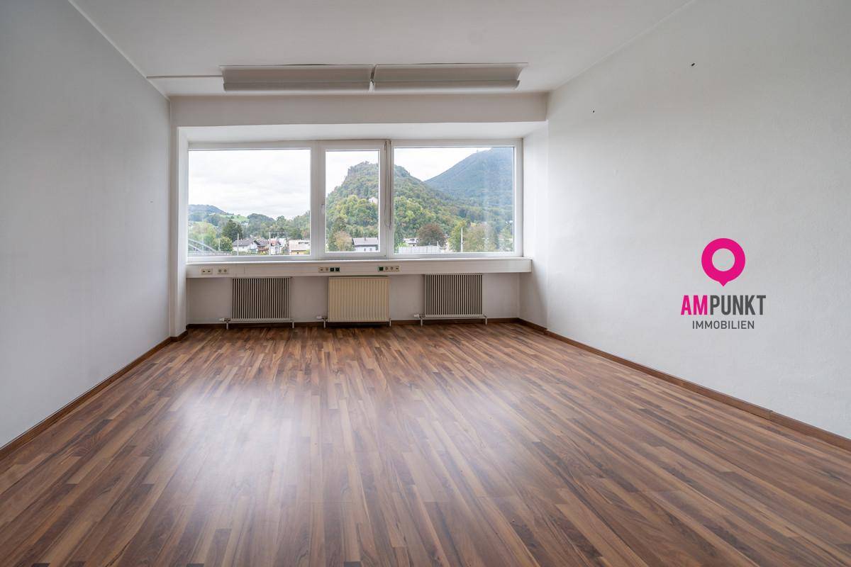 Geräumiger Büroraum mit Holzboden und großen Fenstern, die einen weiten Bergblick ermöglichen.