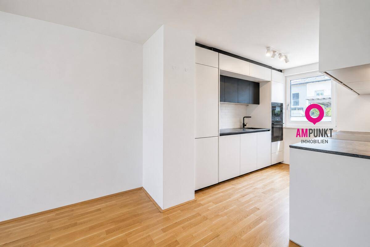 Moderne, eingebaute Küche mit weißen und schwarzen Schränken, bereit für die Nutzung.