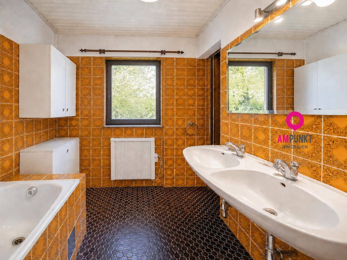 Badezimmer im 80er-Jahre-Stil mit orangefarbenen Fliesen, Doppelwaschbecken und Badewanne.