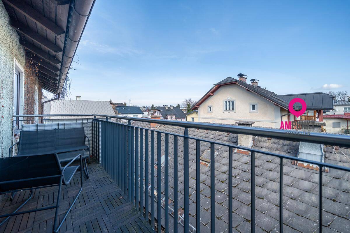 Balkon mit Metallgeländer und Sitzgelegenheiten, bietet einen Blick über die umliegenden Dächer der Nachbarschaft.