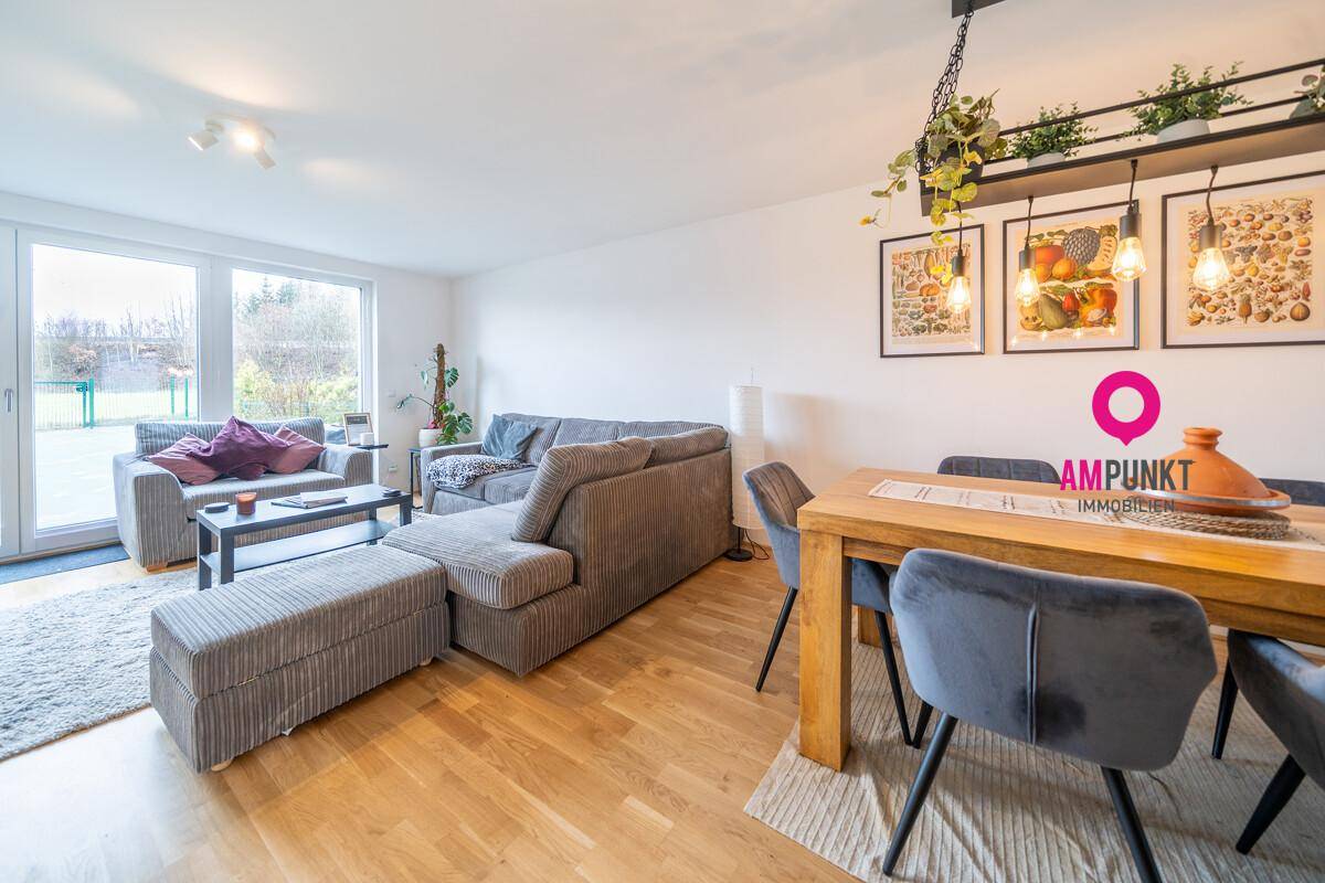 Gemütlicher Wohnbereich mit großzügiger Couch und Zugang zum Garten durch große Fenster.