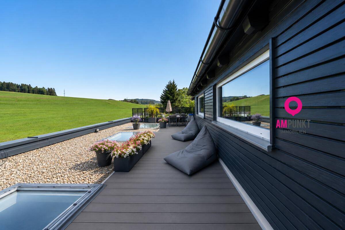 Weitläufige Dachterrasse mit Holzboden und Blick auf die umliegende Natur, ideal zum Entspannen.