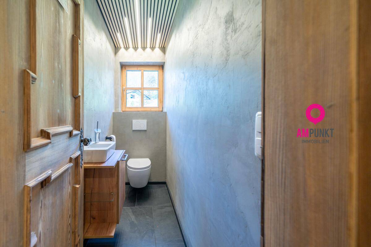 Modernes Gäste-WC mit Holzwaschtisch, Wand-WC und Fenster für Tageslicht.