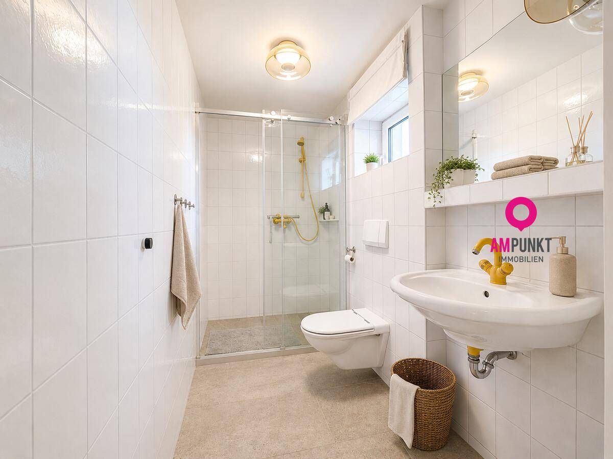 Helles Badezimmer mit weiß gefliesten Wänden, Dusche und modernem Waschtisch mit goldenen Armaturen.