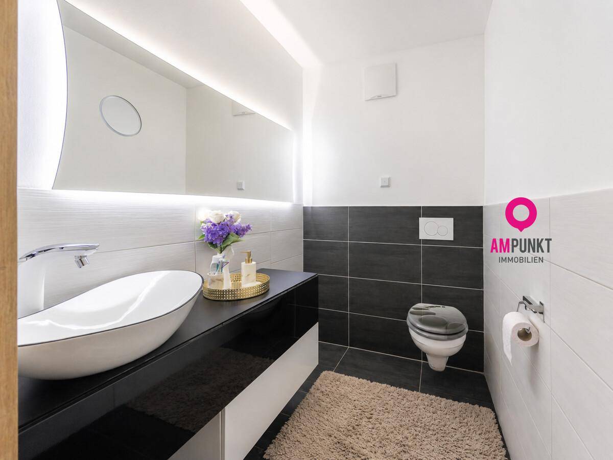 Stilvolles Gäste-WC mit modernem Waschbecken, Wand-WC und dunklen Akzentfliesen.