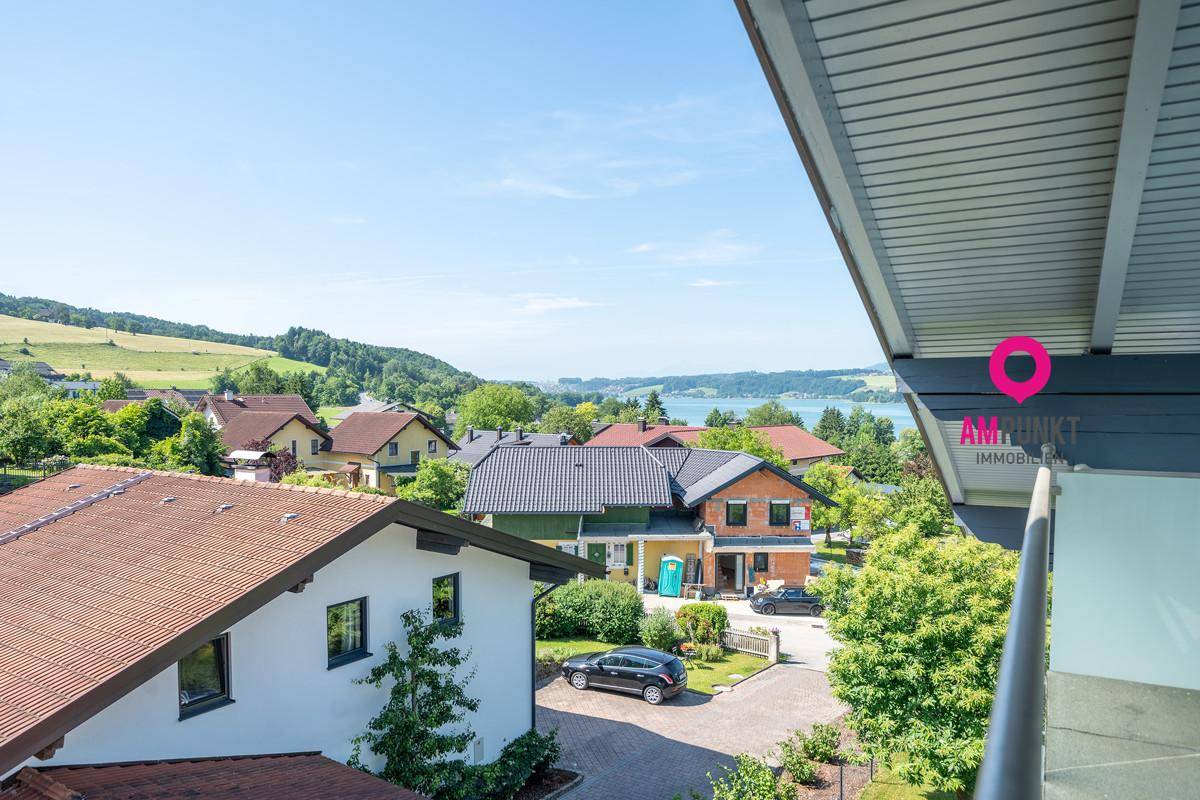 Blick von einem Balkon auf die umliegende Wohnsiedlung mit See und grüner Natur.
