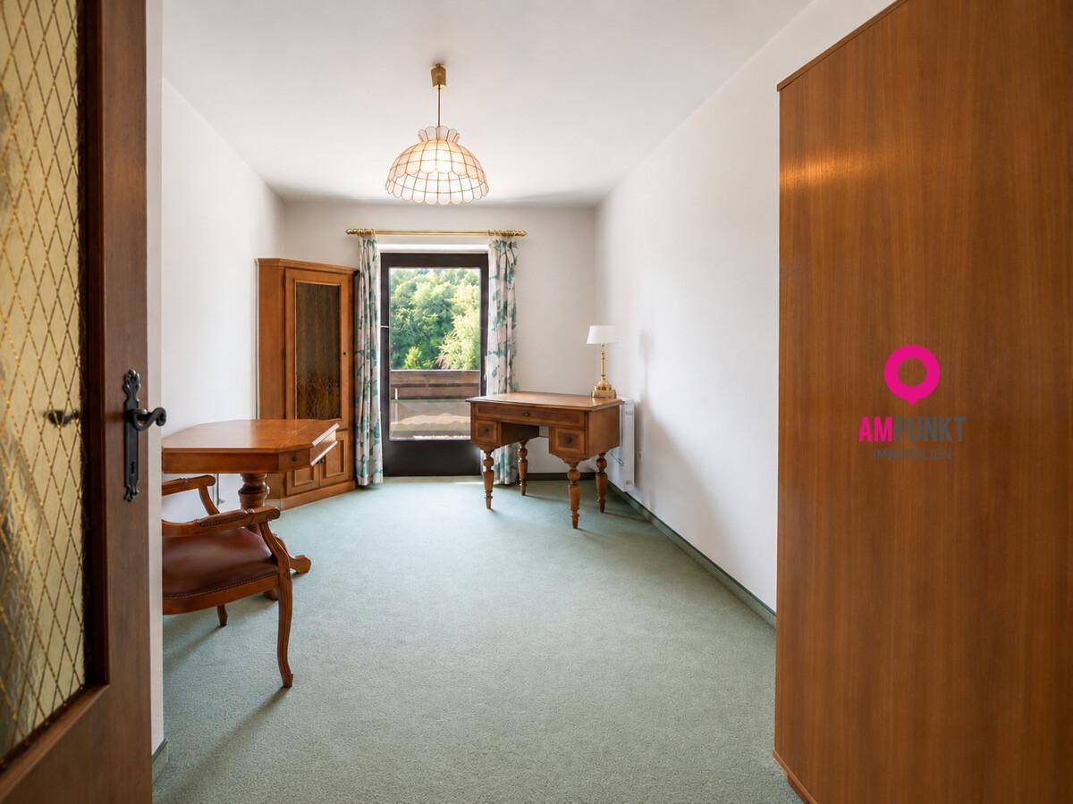 Arbeitszimmer mit Teppichboden, Holzmöbeln und Zugang zu einem Balkon.