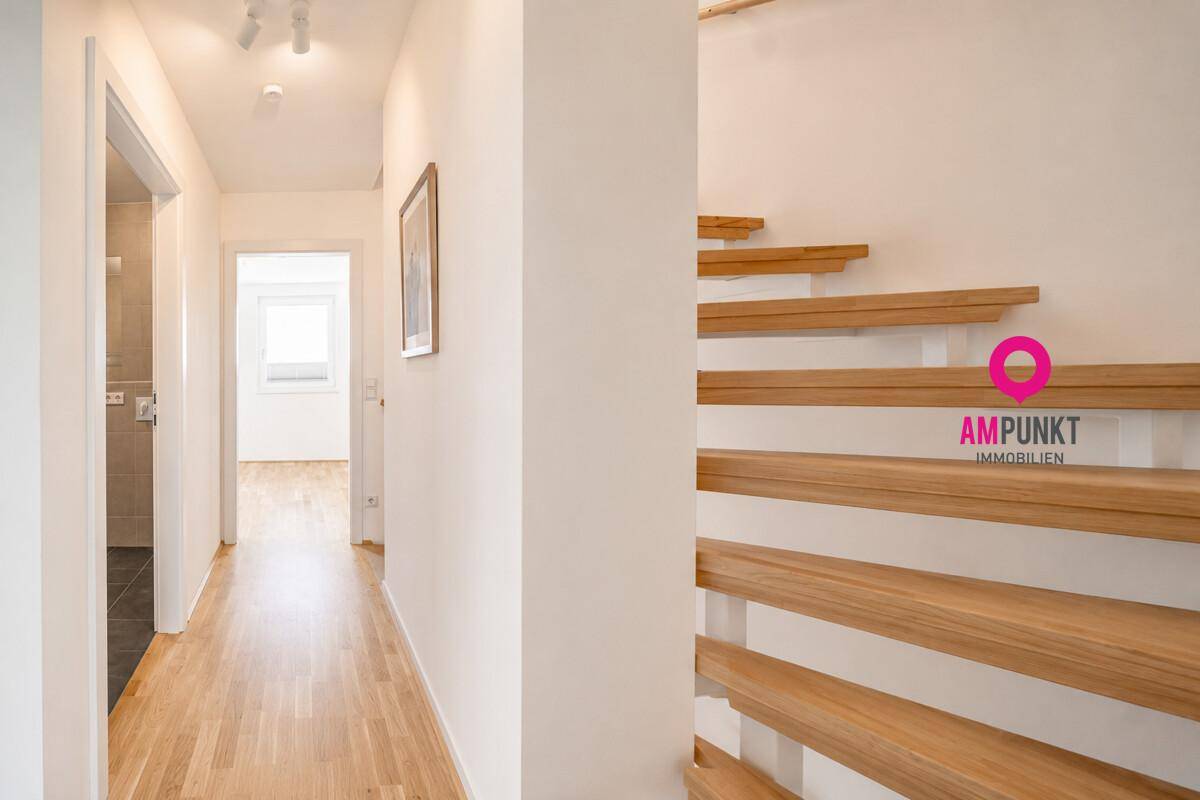 Heller Flur mit Holztreppe und Holzboden, der zu den oberen Etagen führt.