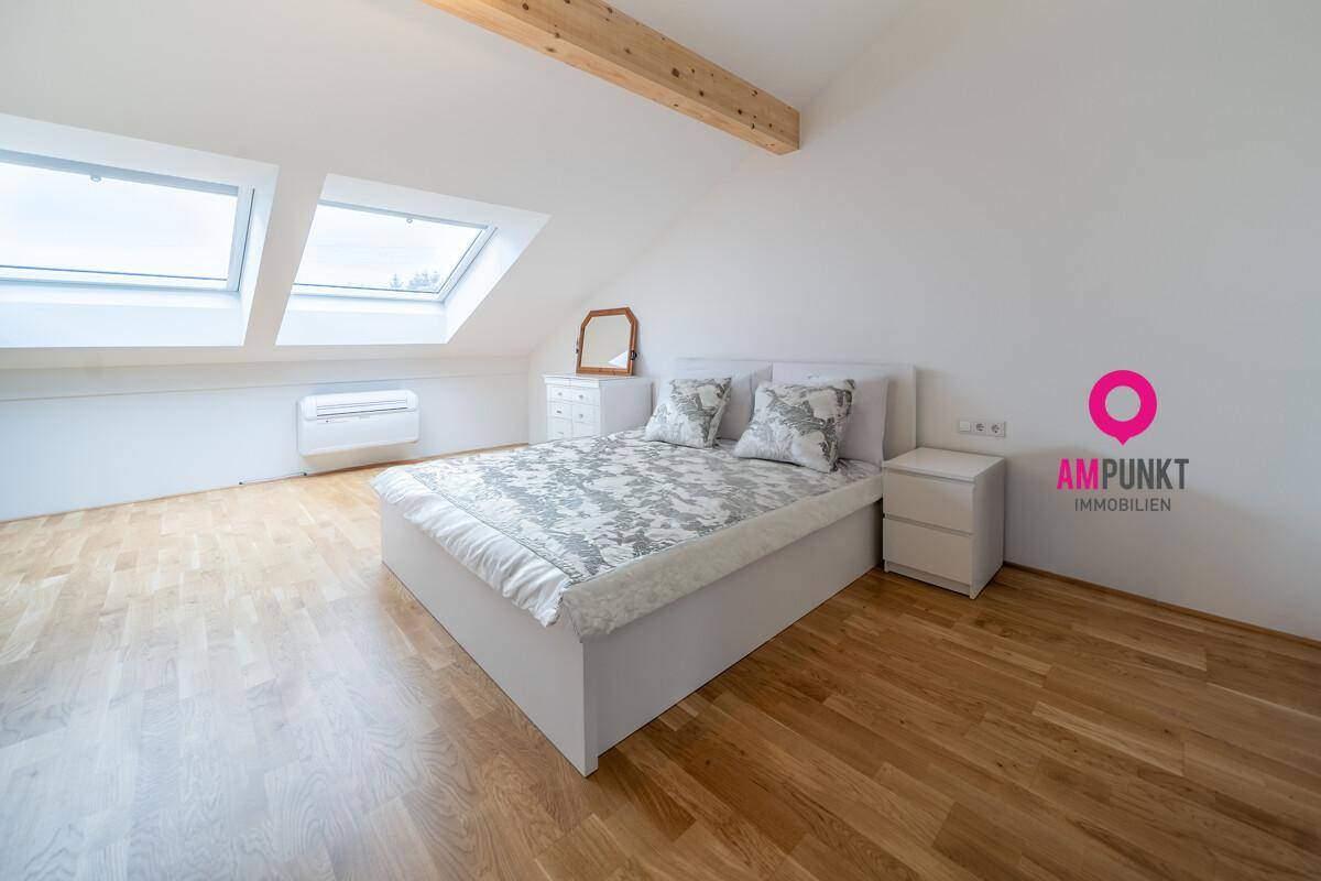 Gemütliches Schlafzimmer im Dachgeschoss mit Holzbalken und Dachfenstern.