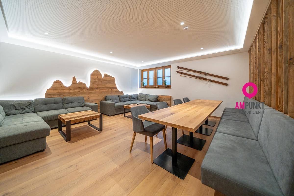 Geräumiger Wohnbereich mit großen Sofas, Holztisch und dekorativer Wandverkleidung, modern und gemütlich gestaltet.