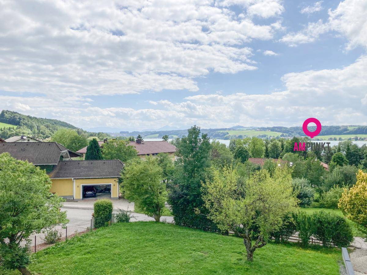 Panoramablick über die umliegende Landschaft mit Häusern und einem See unter bewölktem Himmel.