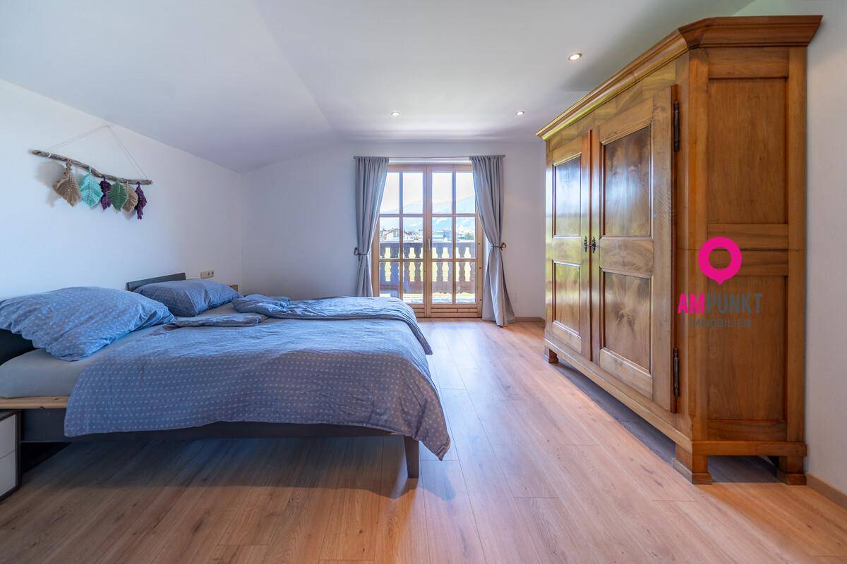 Helles Schlafzimmer mit Holzboden, großem Kleiderschrank und Zugang zum Balkon.