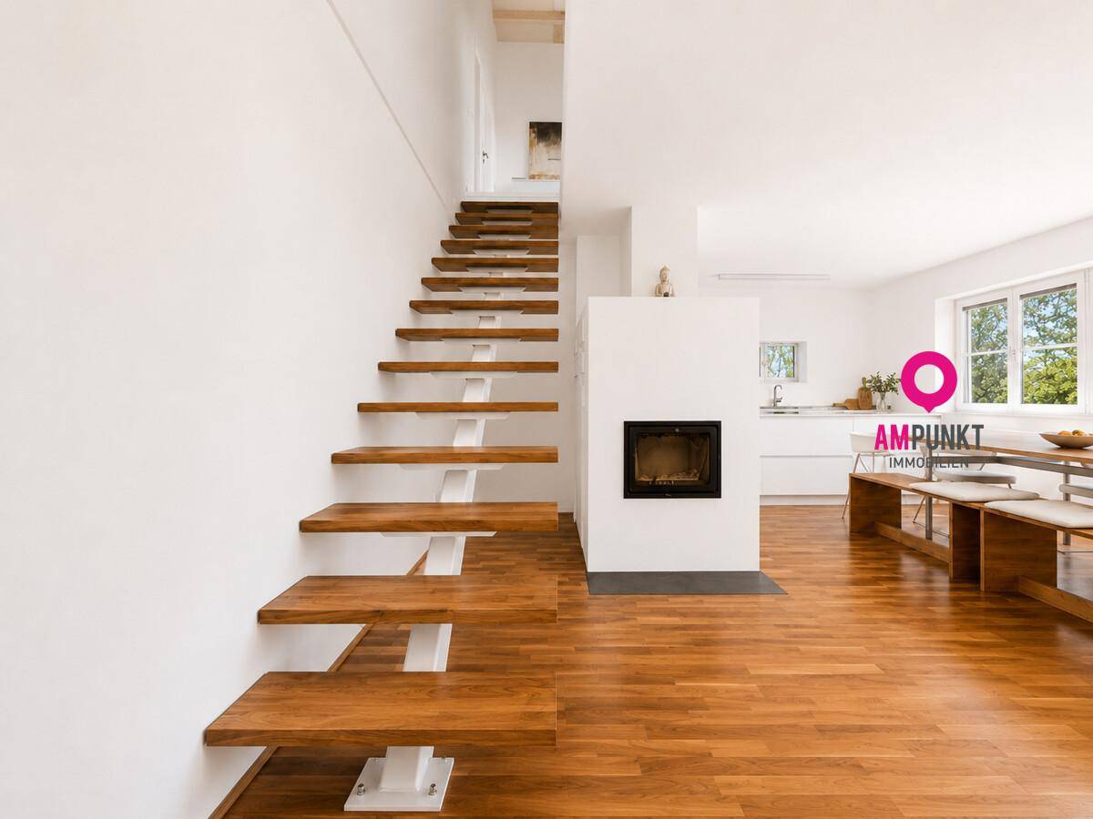 Offener Wohnbereich mit moderner Treppe, Kamin und Blick auf die Küche.