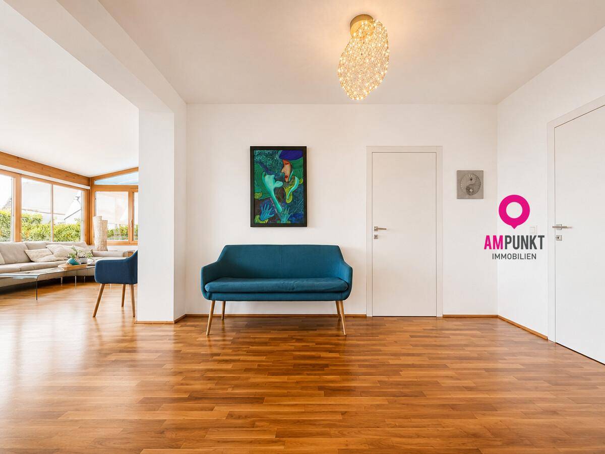 Geräumiger Flur mit Holzboden und einem blauen Sofa, der zum Wohnbereich führt.