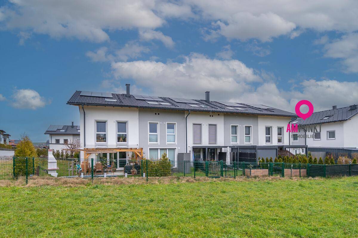 Moderne Reihenhäuser mit Photovoltaikanlage auf dem Dach und großem Gartenbereich.