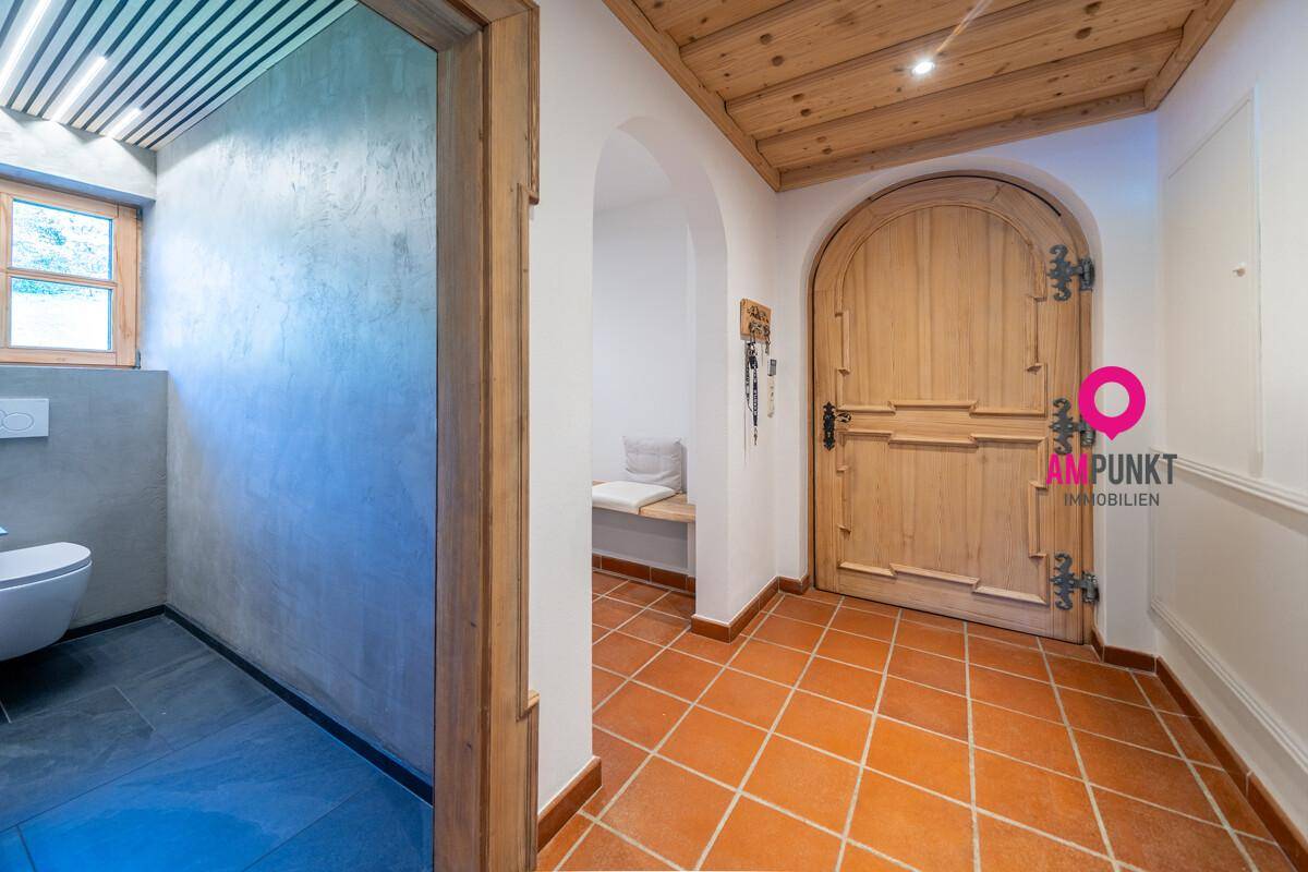 Eingangsbereich mit Terrakottafliesen, Holztür und Zugang zum Gäste-WC.
