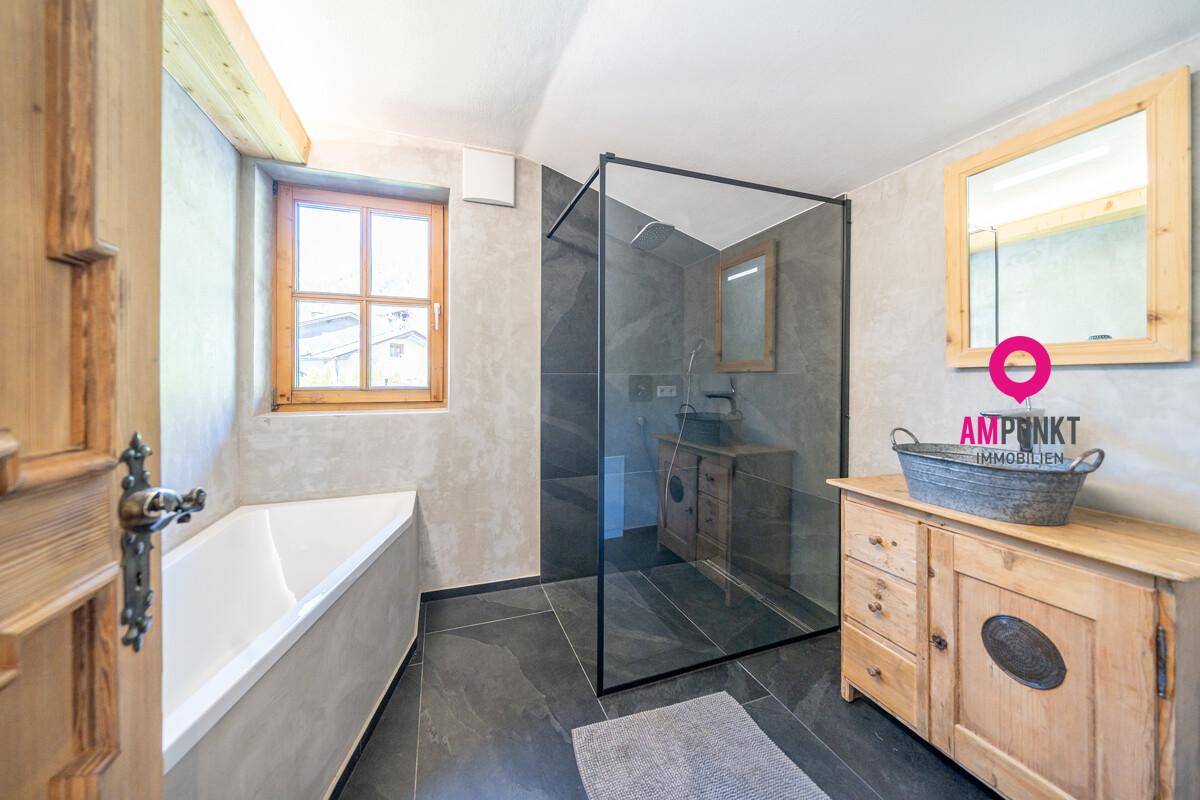 Modernes Badezimmer mit Badewanne, begehbarer Dusche und Fenster für Tageslicht.