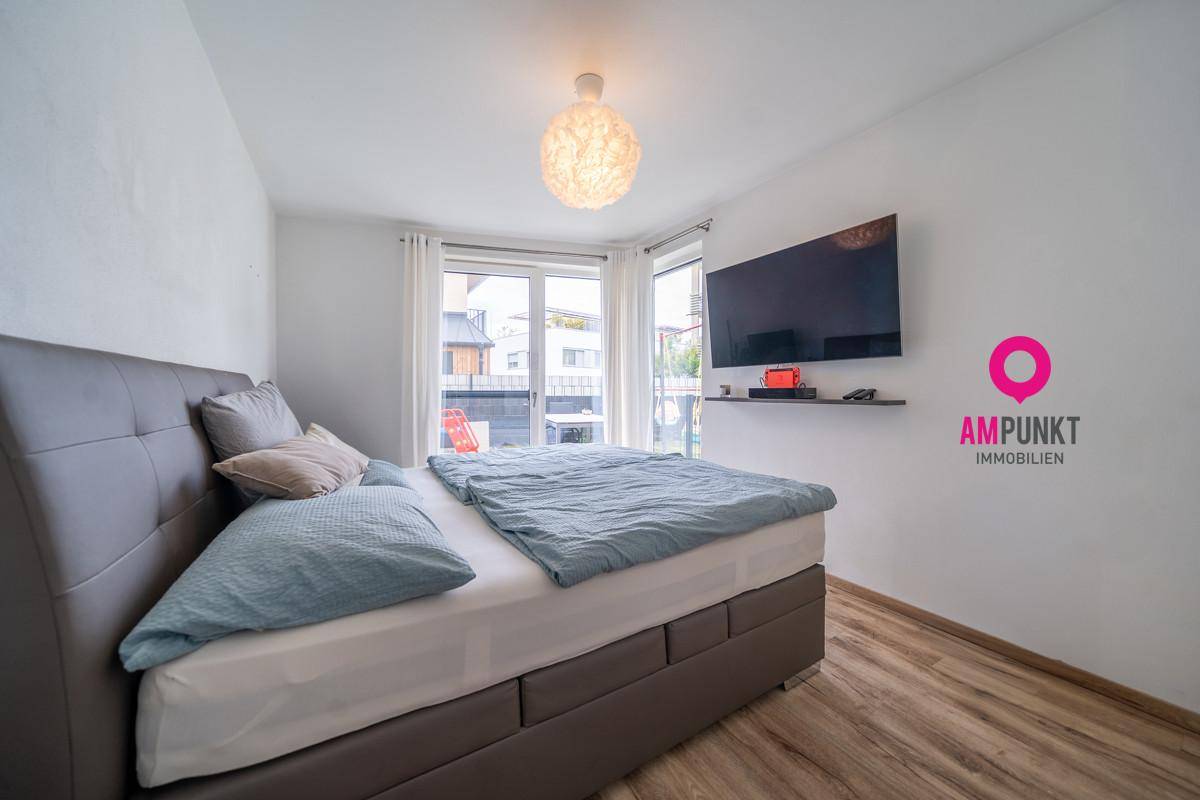 Gemütliches Schlafzimmer mit Doppelbett, Laminatboden und großen Fenstern für viel Licht.