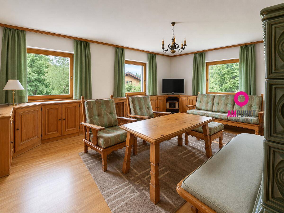 Gemütliches Wohnzimmer im alpinen Stil mit Kachelofen, Holzmöbeln und Blick ins Grüne.