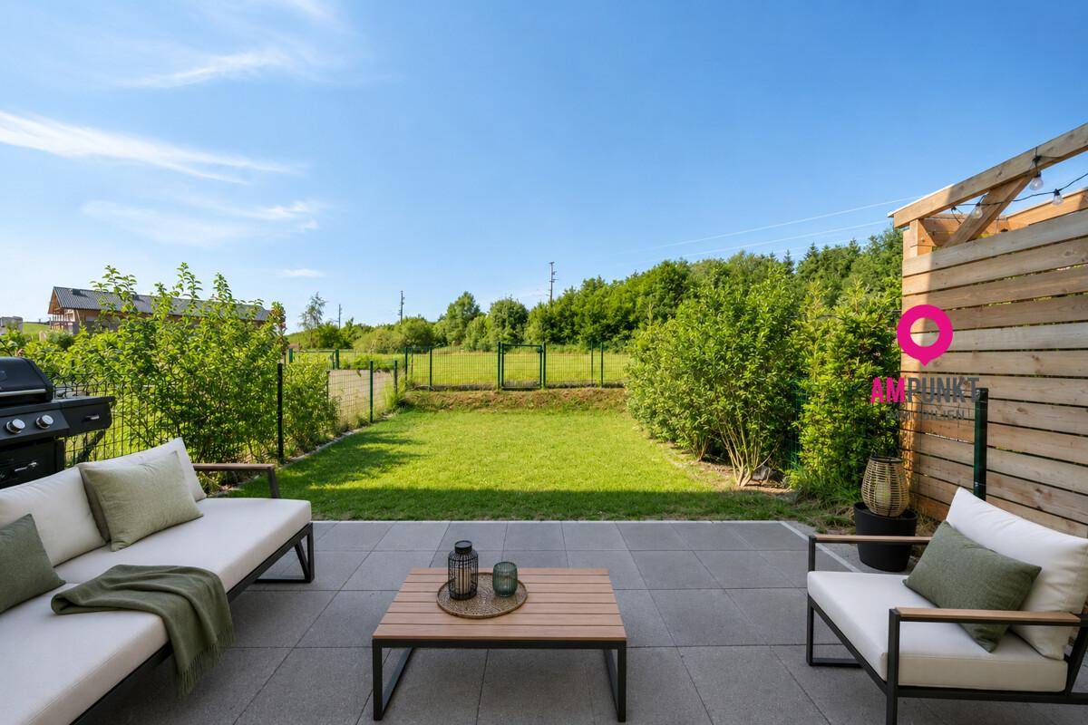 Gemütliche Terrasse mit modernen Gartenmöbeln und Blick auf den grünen Gartenbereich.