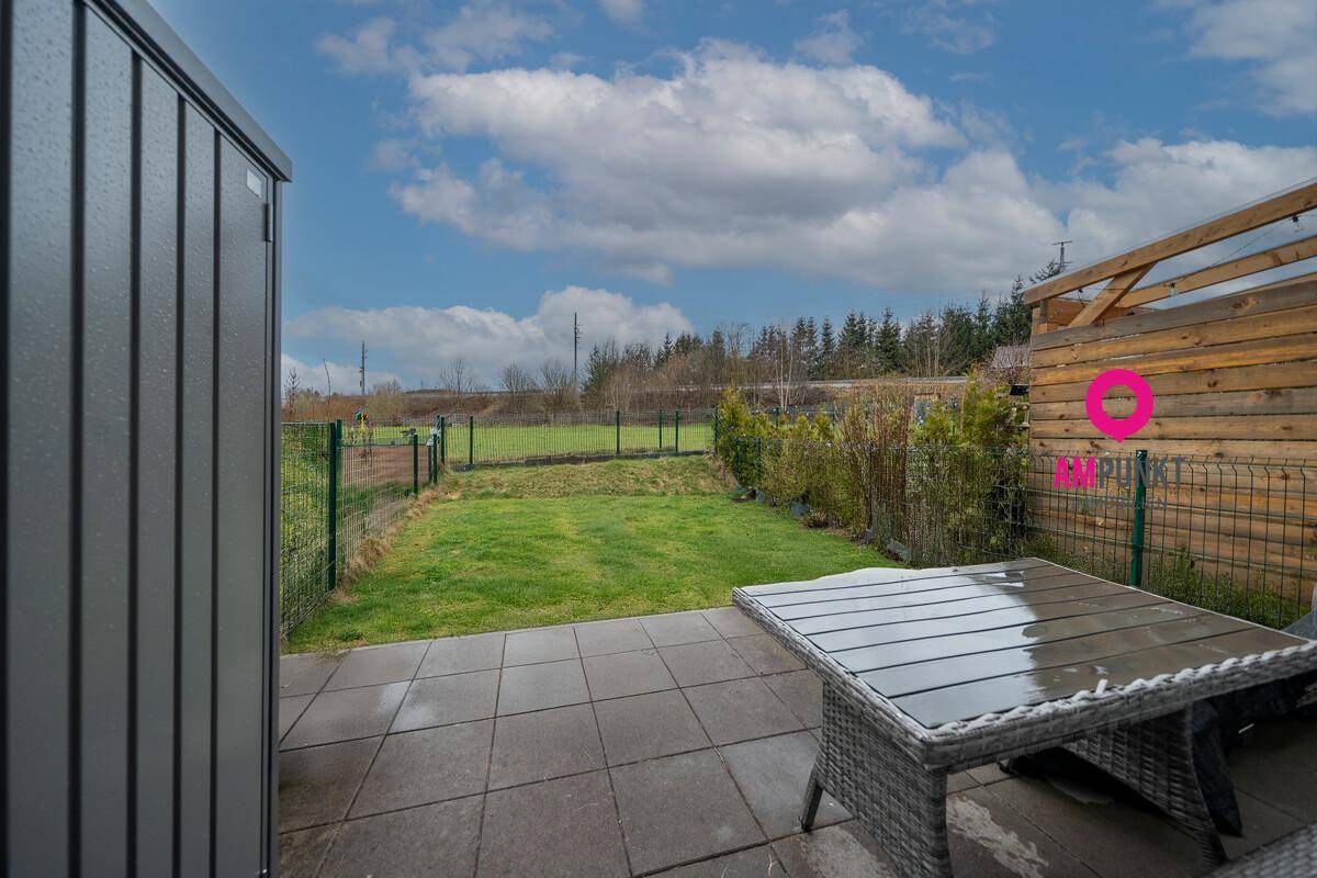 Gepflasterte Terrasse mit Gartenmöbeln und Blick ins Grüne.