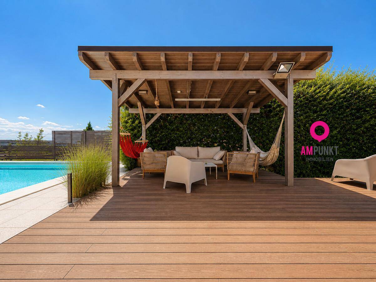 Große Holzterrasse mit Pergola, gemütlicher Sitzecke und Blick auf den Poolbereich.