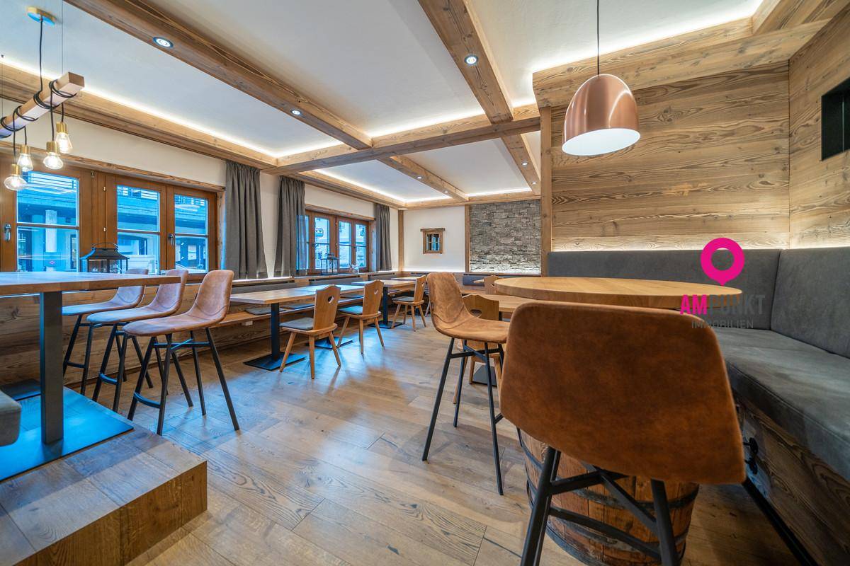Gemütlicher Essbereich mit Holzbalken, modernen Stühlen und indirekter Beleuchtung, kombiniert mit Holzwänden.