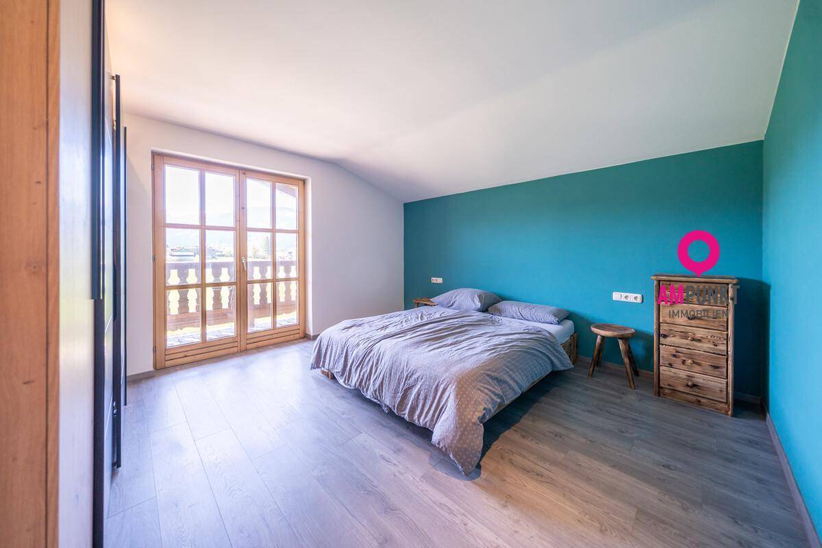 Geräumiges Schlafzimmer mit Holzboden, farbiger Akzentwand und Balkonzugang.