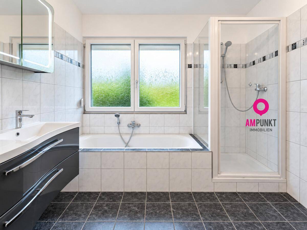 Modernes Badezimmer mit Badewanne, Duschkabine, Einzelwaschbecken und Fenster.