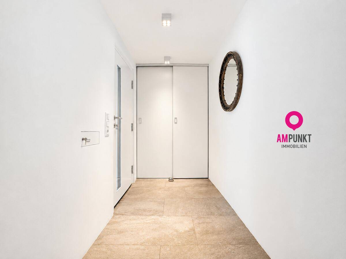 Heller Flur mit Fliesenboden, Spiegelschrank und Zugang zu weiteren Räumen.