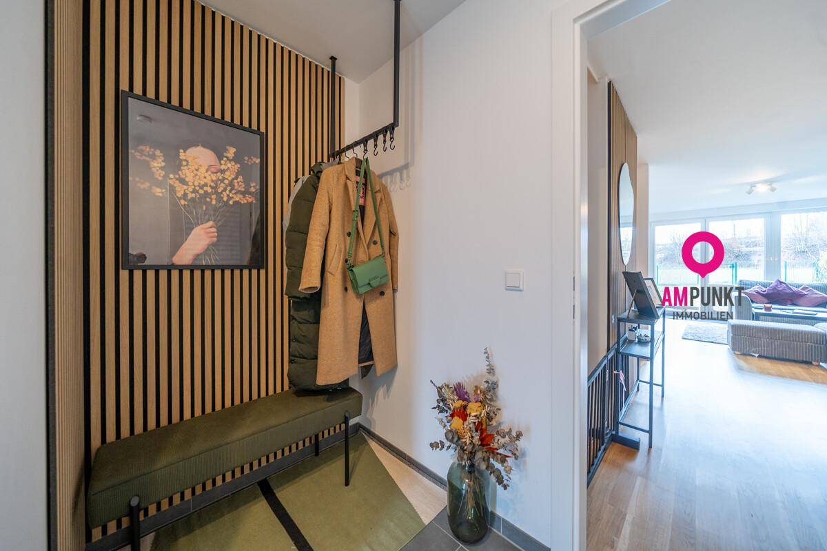 Eingangsbereich mit Garderobe, Sitzbank und dekorativer Holzlamellenwand.