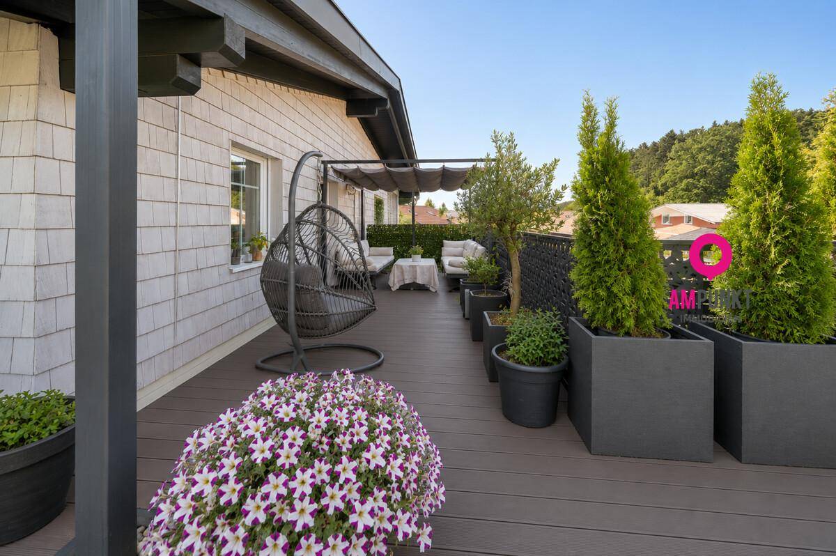 Große Terrasse mit bequemen Sitzgelegenheiten und Pflanzen, ideal zum Entspannen im Freien.