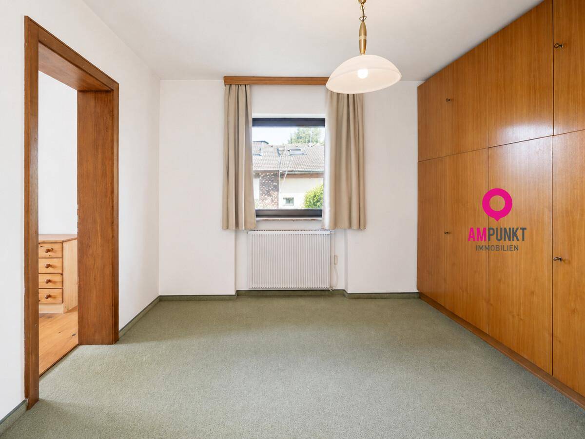Geräumiges Schlafzimmer mit Teppichboden und Einbauschränken aus Holz.