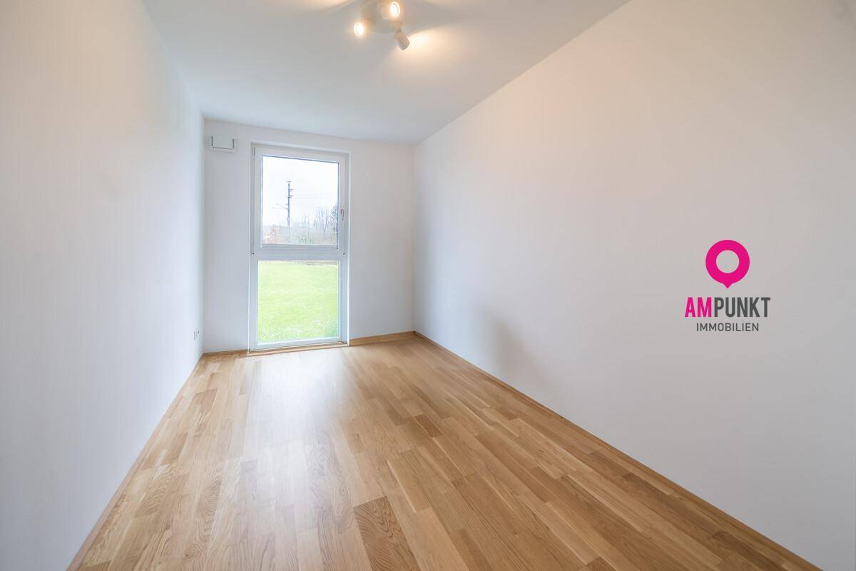 Leeres Zimmer mit Holzboden und Zugang zum Garten.