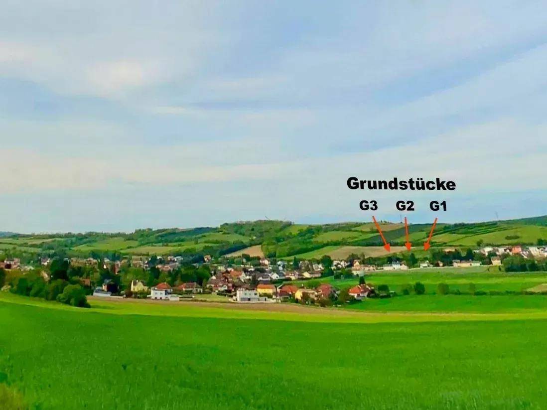 Weitläufige grüne Landschaft mit einem Dorf und den eingezeichneten Baugrundstücken G1, G2 und G3.