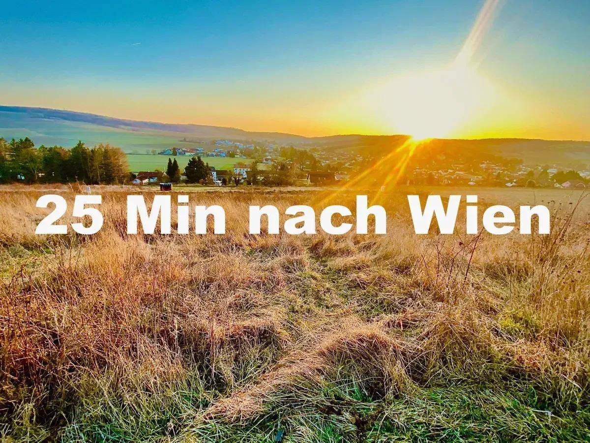 Weitläufiges Feld bei Sonnenuntergang mit dem Hinweis auf die kurze Fahrzeit nach Wien.