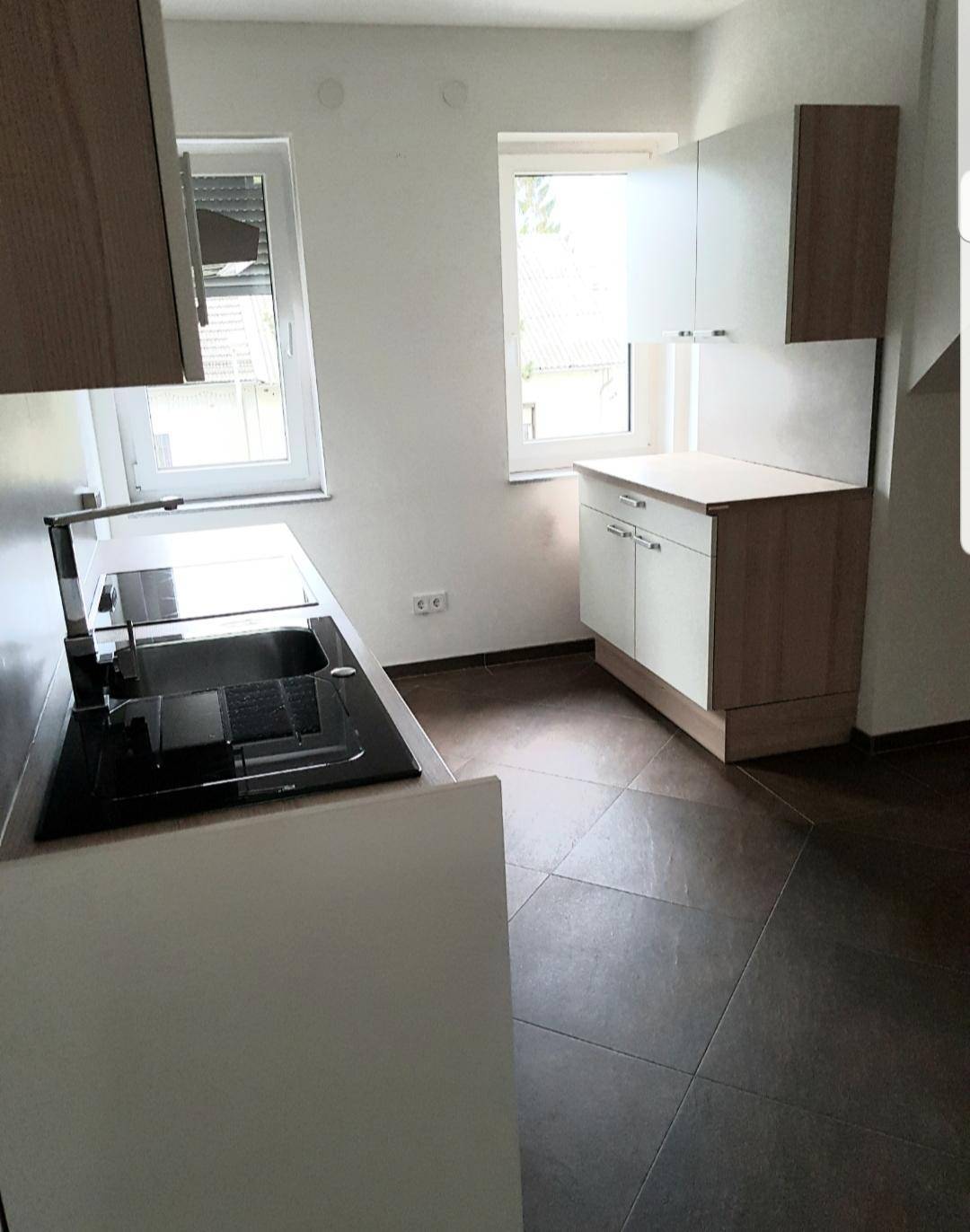Moderne Küche mit Fenster, Spüle und Induktionskochfeld, ausgestattet mit hellen Schränken.