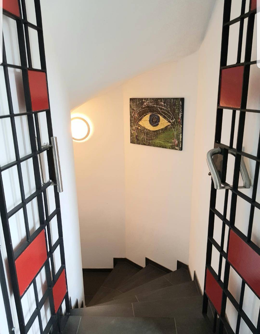 Treppenhaus mit künstlerischer Wanddekoration und dekorativen Metallgittern im modernen Stil.