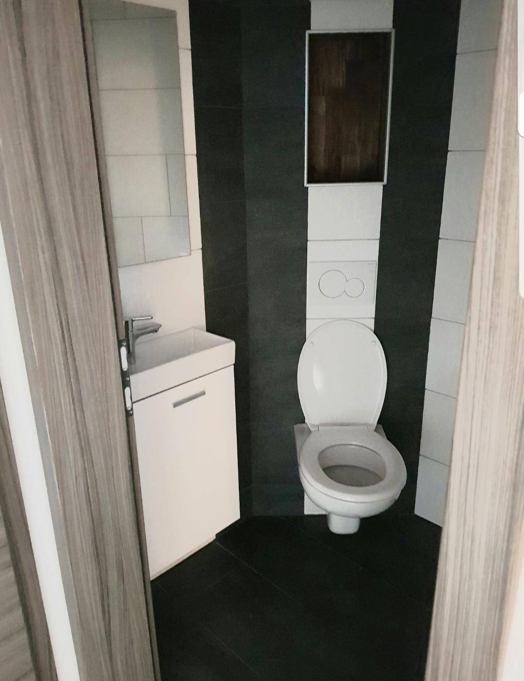 Modernes Gäste-WC mit gestreiften Fliesen, wandhängendem WC und kleinem Waschbecken.